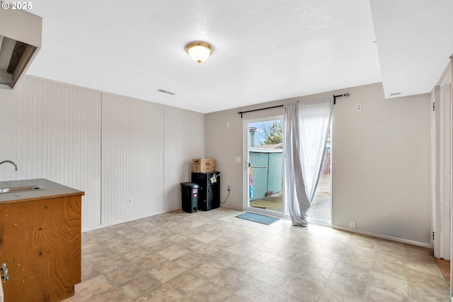 empty room with light floors, visible vents, and a sink