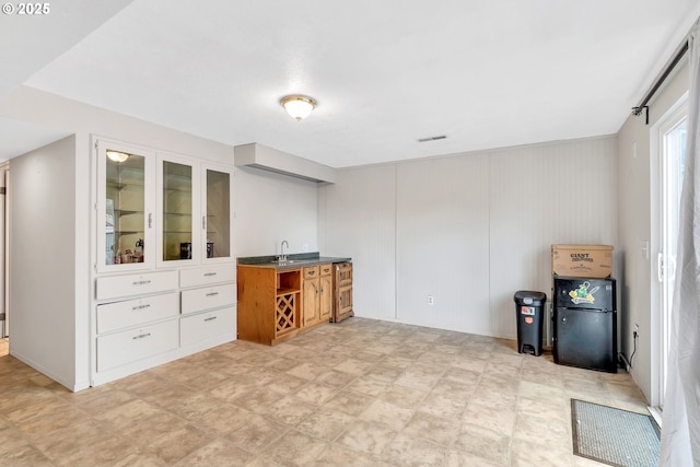 interior space with light floors, visible vents, a sink, and freestanding refrigerator