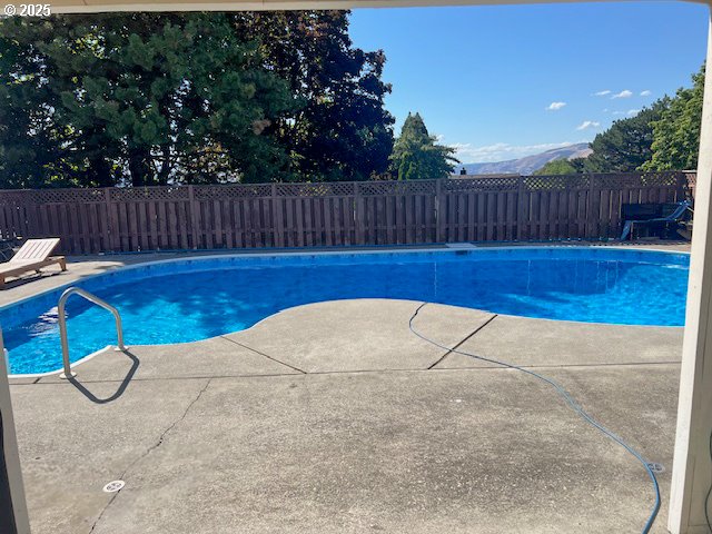 view of swimming pool featuring a patio area, a fenced backyard, a mountain view, and a fenced in pool