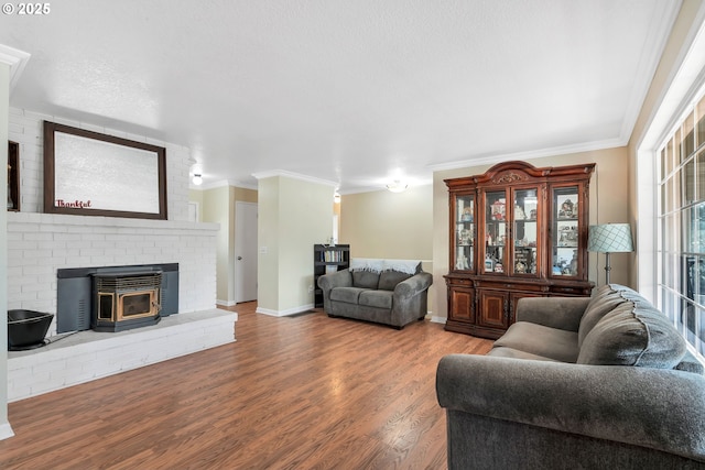 living room featuring ornamental molding, a wood stove, baseboards, and wood finished floors