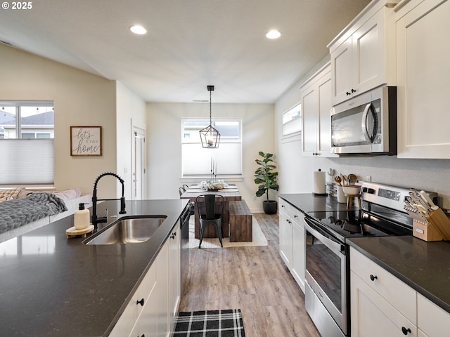 kitchen featuring sink, light hardwood / wood-style flooring, appliances with stainless steel finishes, pendant lighting, and white cabinets