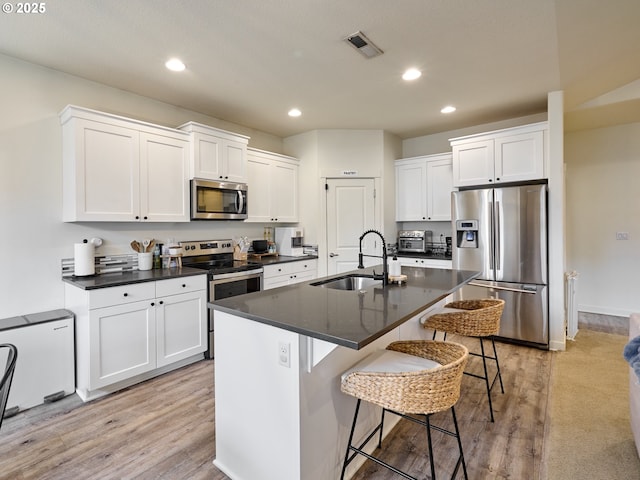 kitchen featuring an island with sink, white cabinetry, sink, a breakfast bar area, and stainless steel appliances