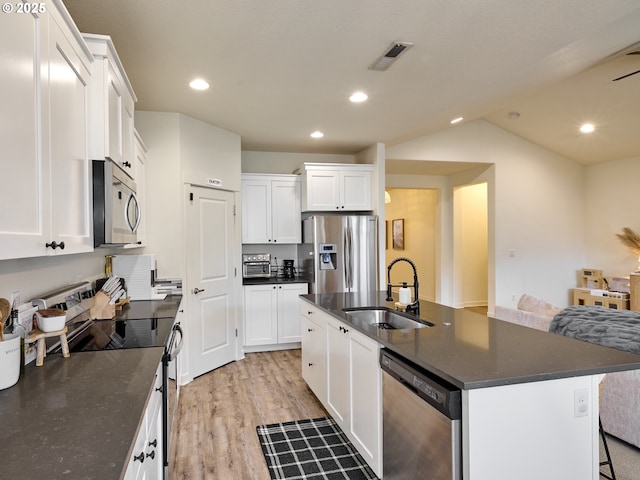 kitchen with a sink, stainless steel appliances, light wood-style floors, vaulted ceiling, and white cabinetry