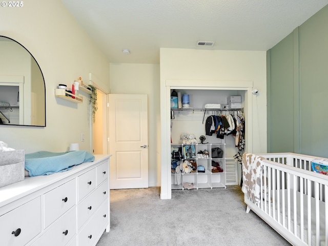 bedroom featuring a nursery area, light carpet, and a closet