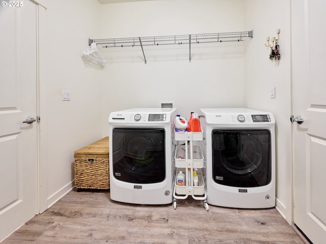 clothes washing area featuring washer and clothes dryer and light hardwood / wood-style floors