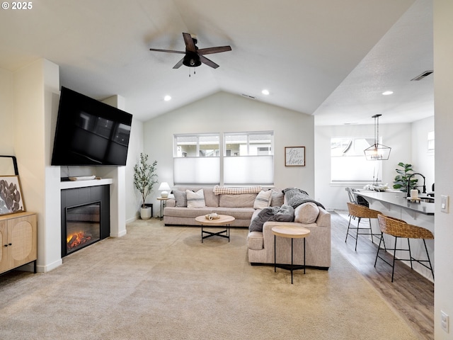 living room featuring vaulted ceiling, light colored carpet, and ceiling fan