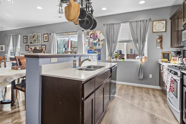 kitchen with a wealth of natural light, dark brown cabinets, stainless steel range with gas cooktop, and a sink