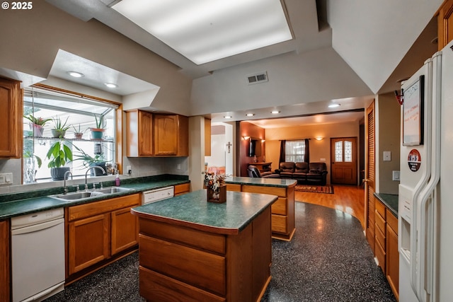 kitchen featuring a healthy amount of sunlight, sink, a center island, and white appliances