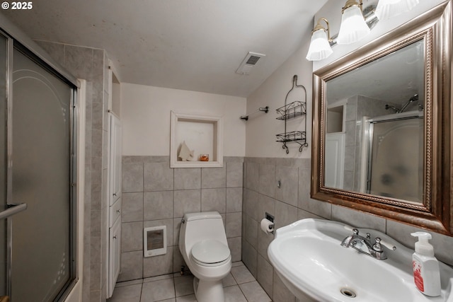 bathroom with toilet, tile patterned flooring, tile walls, an enclosed shower, and sink