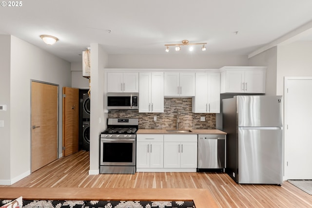 2021 SE Clinton St Unit 103, Portland, OR 97202 - kitchen with stainless steel appliances, estacked washer and dryer, light wood finished floors, and white cabinets