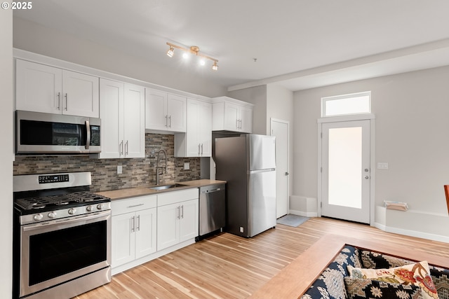 2021 SE Clinton St Unit 103, Portland, OR 97202 - kitchen with appliances with stainless steel finishes, tasteful backsplash, light wood-style flooring, and white cabinets