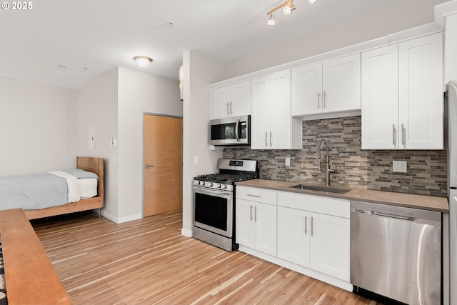2021 SE Clinton St Unit 103, Portland, OR 97202 - kitchen with stainless steel appliances, light wood finished floors, tasteful backsplash, white cabinets, and light countertops