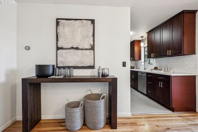 bar featuring stainless steel dishwasher, light wood finished floors, and baseboards