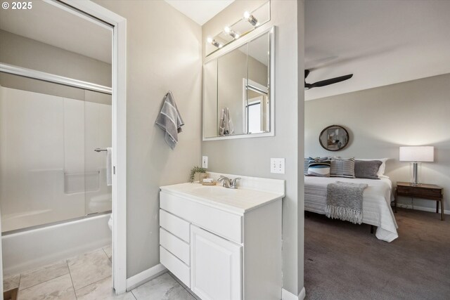 ensuite bathroom with ceiling fan, vanity, baseboards, and shower / bath combination with glass door