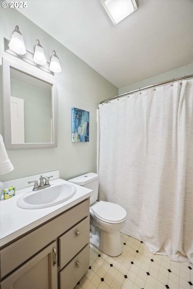 full bath featuring toilet, vanity, tile patterned floors, and curtained shower