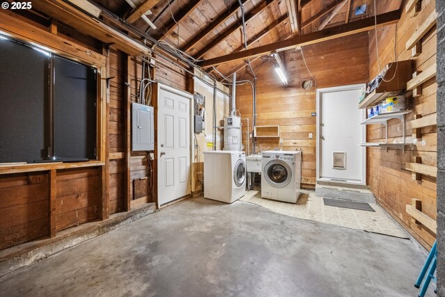 laundry room with washing machine and clothes dryer, wooden walls, electric panel, and a sink