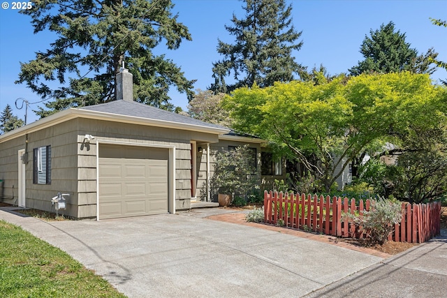 view of front of house featuring an attached garage, a chimney, concrete driveway, and fence