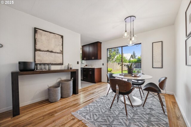 dining area with light wood-type flooring and baseboards