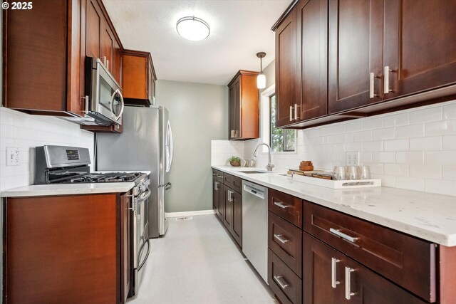 kitchen featuring appliances with stainless steel finishes, a sink, tasteful backsplash, and baseboards