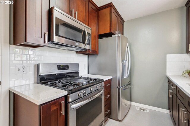 kitchen featuring appliances with stainless steel finishes, tasteful backsplash, baseboards, and light stone countertops