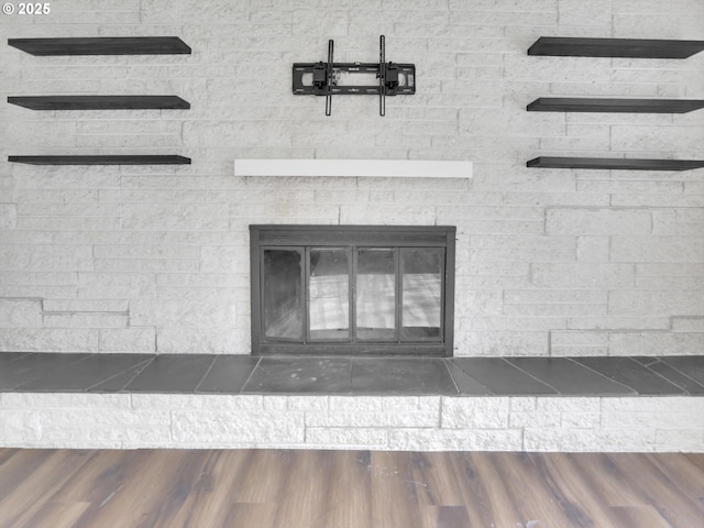 interior details with wood finished floors and a glass covered fireplace