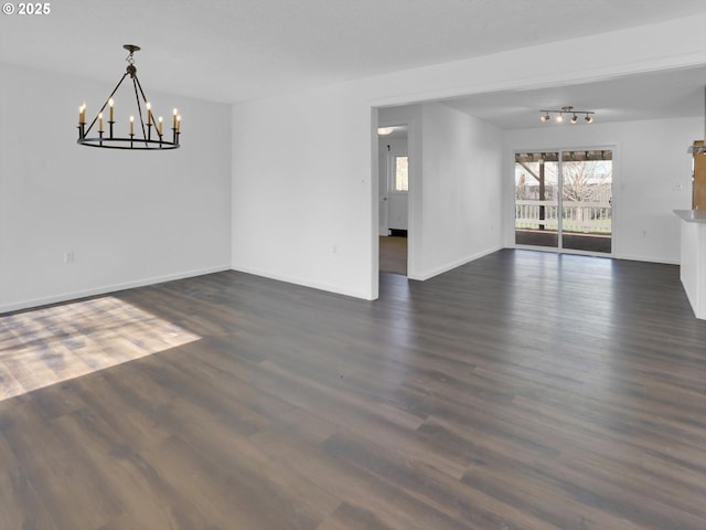 unfurnished dining area with a notable chandelier, dark wood-style flooring, and baseboards