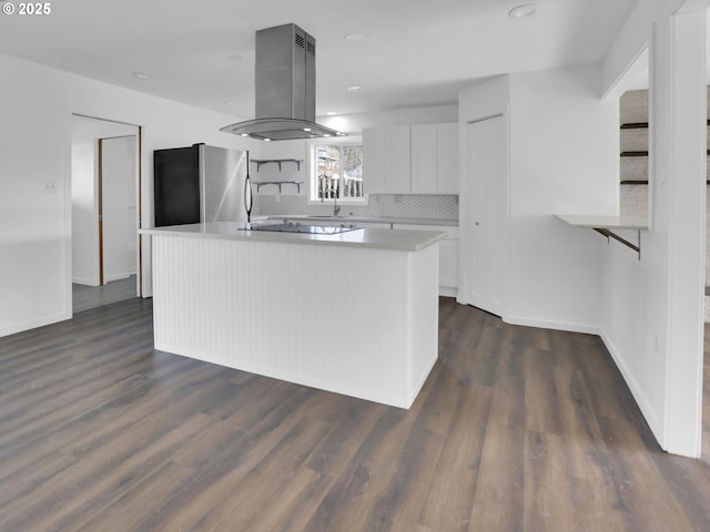 kitchen with white cabinets, dark wood finished floors, a kitchen island, freestanding refrigerator, and island exhaust hood