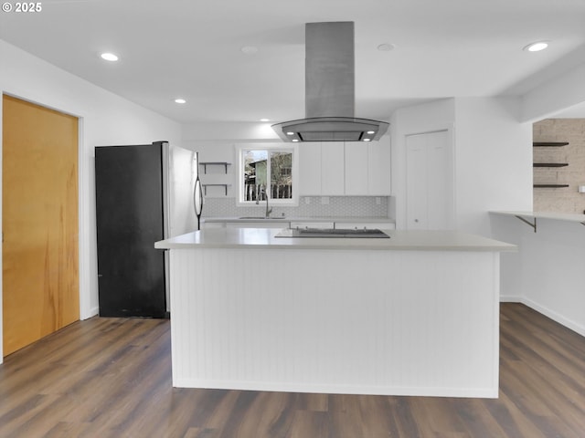 kitchen featuring island range hood, freestanding refrigerator, white cabinetry, open shelves, and a sink