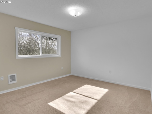 carpeted spare room with visible vents and baseboards