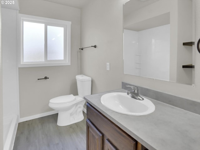 bathroom with toilet, baseboards, wood finished floors, and vanity