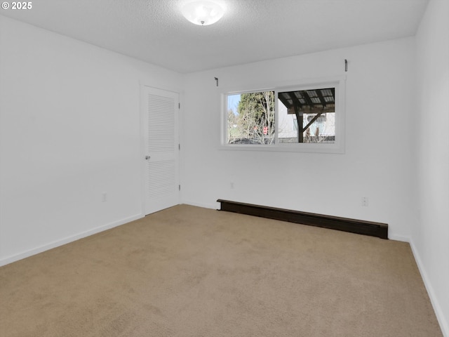 unfurnished room with carpet, a baseboard radiator, baseboards, and a textured ceiling