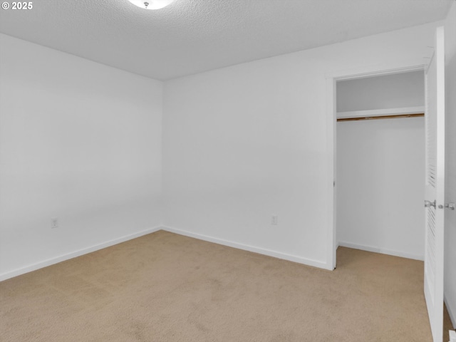 unfurnished bedroom with a textured ceiling, carpet floors, a closet, and baseboards