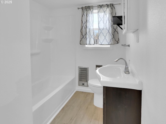 bathroom with toilet, vanity, heating unit, and wood finished floors