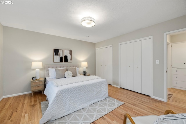 bedroom featuring multiple closets and light wood-type flooring