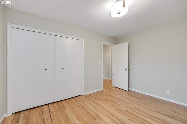 unfurnished bedroom with light hardwood / wood-style flooring, a closet, and a textured ceiling