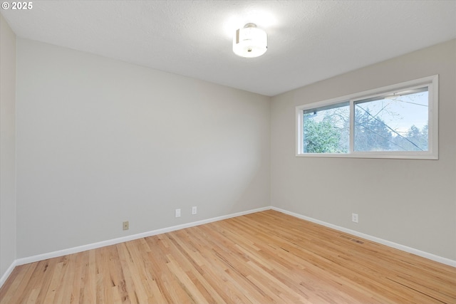 unfurnished room with light hardwood / wood-style flooring and a textured ceiling