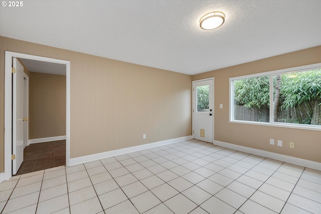 spare room with a textured ceiling and light tile patterned floors