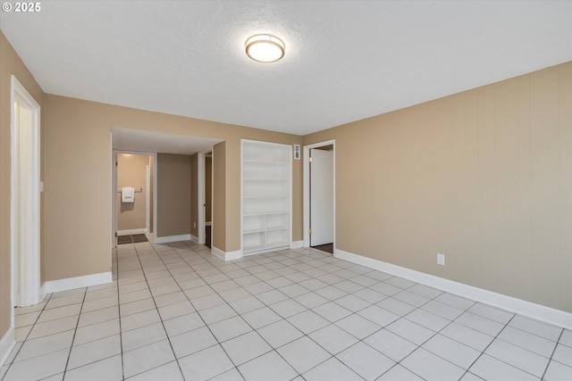 tiled spare room with built in features and a textured ceiling