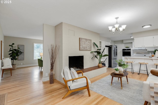 living room with an inviting chandelier, a fireplace, and light hardwood / wood-style flooring