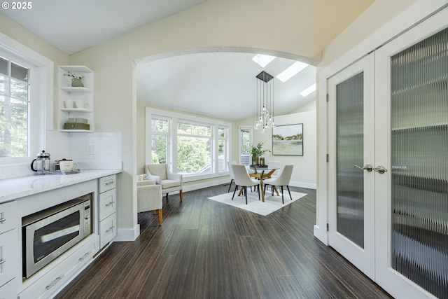 32518 Dillard Rd, Eugene, OR 97405 - kitchen with arched walkways, stainless steel microwave, lofted ceiling, light stone counters, and a chandelier