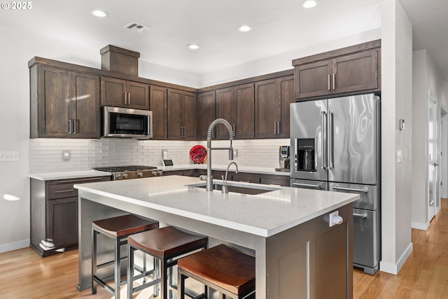 kitchen with sink, stainless steel appliances, a kitchen breakfast bar, and an island with sink