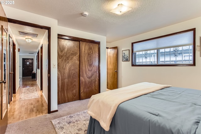 bedroom featuring a textured ceiling, light carpet, and a closet