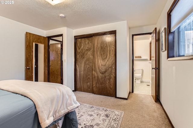 bedroom with carpet flooring, connected bathroom, a textured ceiling, and baseboards