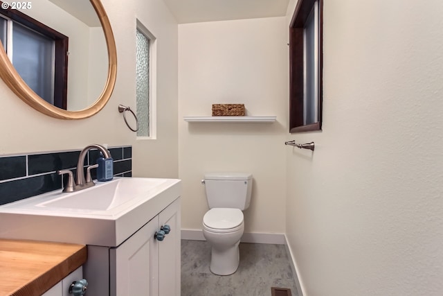 half bath with vanity, baseboards, and toilet