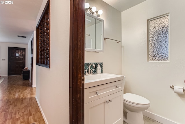 bathroom featuring baseboards, toilet, vanity, and wood finished floors