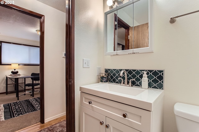 bathroom with toilet, vanity, and wood finished floors