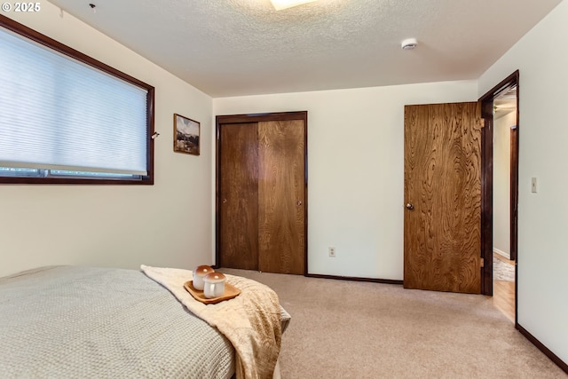 bedroom with a closet, carpet, baseboards, and a textured ceiling