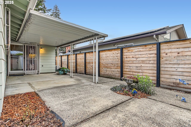 view of patio / terrace featuring a fenced backyard, a carport, and concrete driveway