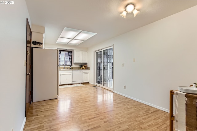 kitchen featuring freestanding refrigerator, dishwasher, light wood-style floors, and white cabinets