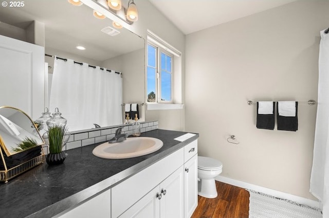 bathroom featuring baseboards, visible vents, toilet, wood finished floors, and vanity